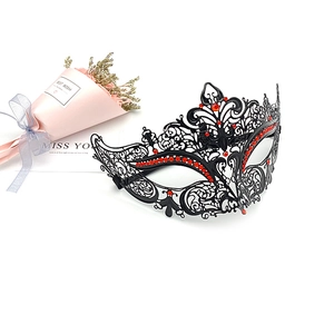 Detail of black filigree metal mask with red rhinestones for masquerade parties