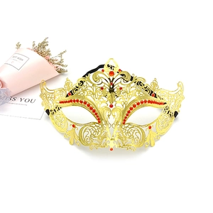 Detail shot of golden filigree masquerade mask with red rhinestones on a white background