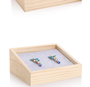 Close-up of a solid wood jewelry tray with grey velvet lining and dragonfly earrings