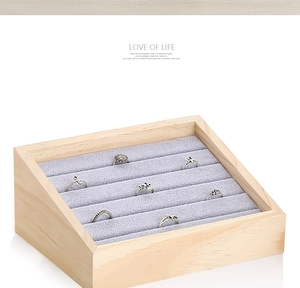 Macro shot of slanted wooden jewelry tray with gray velvet slots for ring display