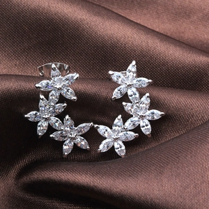 Macro shot of silver floral earrings with marquise AAA zircon on brown silk