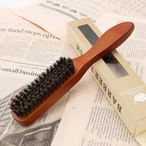 Men's wooden beard brush with natural boar bristles and packaging on newspaper background