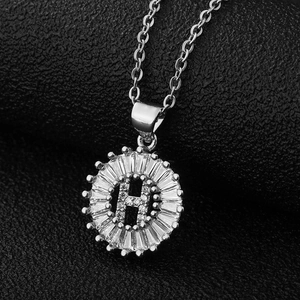 Vue macro du pendentif lettre H en argent avec zircons sur fine chaîne croisée