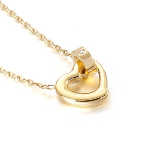 Elegant gold hollow heart necklace with a sparkling small clear gemstone on white background