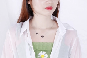 Dettaglio di una collana d'argento con doppio ciondolo a cuore indossata da una modella
