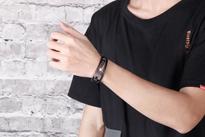 Close-up of men's multi-layer black braided leather bracelet with guitar metal charm