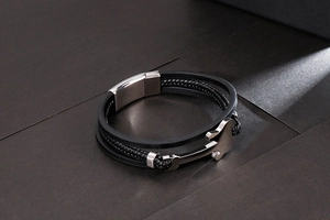 Detailed view of multilayer black woven leather bracelet with silver anchor charm