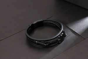 Detail of multi-strand black braided leather bracelet with heart puzzle metal clasp