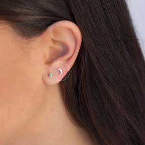 Close-up of minimalist gold crescent moon and turquoise stud earrings on ear model