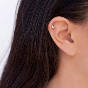 Elegant gold crescent moon stud earring worn on earlobe for minimalist style