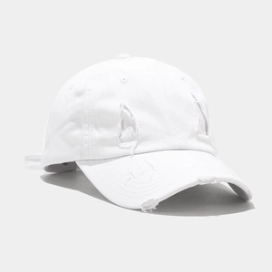 Detailed close-up of distressed white cotton baseball cap with vintage frayed hole details