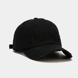Detailed view of distressed holes and cotton fabric texture on a black vintage baseball cap