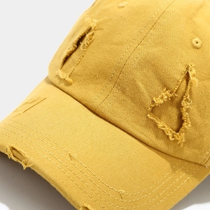 Close-up of yellow distressed baseball cap with vintage worn-out details and premium stitching