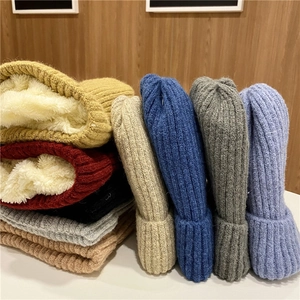 Winter knit beanies with thick fleece lining shown in various colors on wooden background