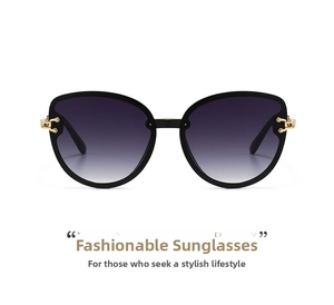 Detail of black cat-eye sunglasses featuring a gold C-shape buckle and gradient lenses