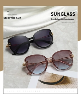 Detail of oversized cat-eye sunglasses with luxury metal chain arms on white silk