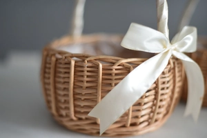 Detail of hand-woven wood flower basket featuring a delicate creamy white satin bow