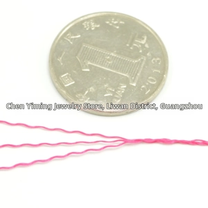Macro view of rose pink wavy polyester thread coils for DIY jewelry with coin size guide