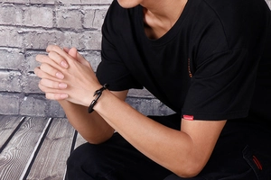 Close-up of men's black woven leather bracelet with a black metal fishhook clasp