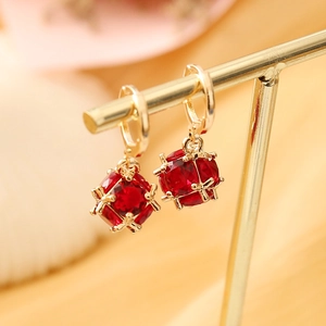 Macro shot of gold hoop earrings featuring a red round crystal sphere in a cage pendant