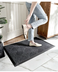 Close-up of dark grey geometric woven doormat with non-slip rubber border in home entryway