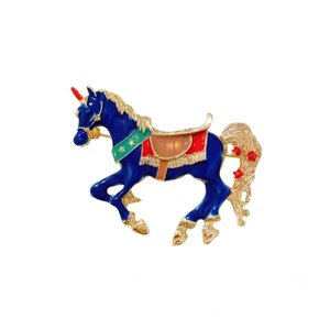 Deep blue enamel unicorn brooch with gold trim and green star-patterned collar on white background
