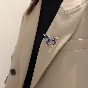 Detail of dark blue enamel unicorn brooch with gold trim pinned on a khaki suit blazer
