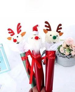 Close-up of DIY Christmas flower decorations with plush Santa and reindeer floral toppers