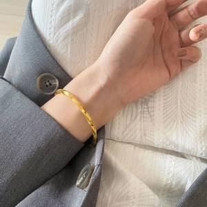 Detail eines gedrehten Mobius-Armbands aus 18K vergoldetem Edelstahl am Handgelenk