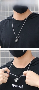 Macro detail of silver guitar pendant with rope chain on stainless steel necklace