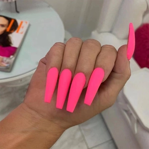 Long ballerina press-on nails in bright pink color shown on a hand with ELLE magazine
