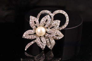 Macro shot of silver flower brooch with sparkling rhinestones and a large center pearl