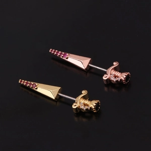 Macro shot of sword-shaped stud earrings in rose gold and gold with zircon stones