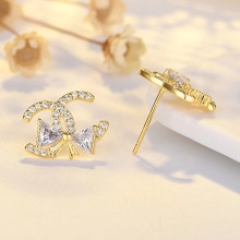 Macro shot of gold double C earrings with bow pendant and shimmering micro-set diamonds