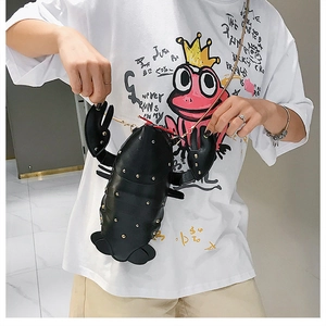 Detail of creative black lobster crossbody bag with gold studs and metal chain strap