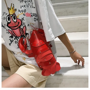 Detail of red lobster crossbody bag with gold chain strap on a white staircase