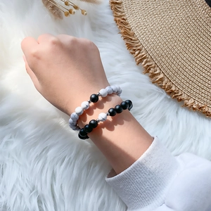 Detail of couple magnetic bracelets with black and white natural stone beads on soft fur