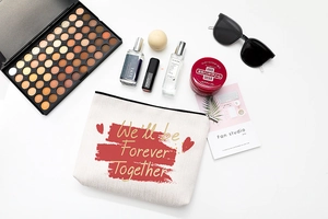 Flat lay of white canvas makeup bag with Forever Together text and beauty accessories
