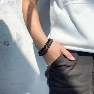 Detail of natural tiger eye and lava stone magnetic couple bracelets on a model