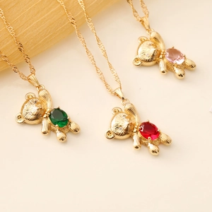 Detailed shot of gold bear necklaces featuring green, red, and pink gemstones on wave chains
