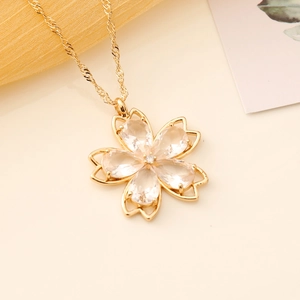 Macro shot of cherry blossom necklace with pink zircon petals and golden singapore chain