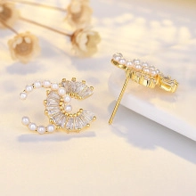 Macro view of gold-tone interlocking C earrings with white pearls and clear zircons