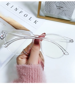 Close-up of clear oversized round glasses held by a model for a trendy aesthetic look
