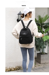 Outdoor shot of stylish black nylon backpack with multi-zipper layers and side pockets