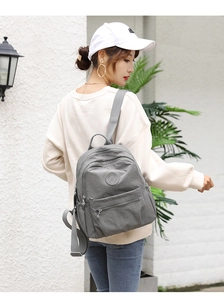 Outdoor shot of a woman wearing a minimalist grey waterproof nylon backpack with silver zips