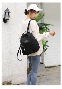 Close-up of black nylon casual backpack with zipper pocket and round leather logo patch
