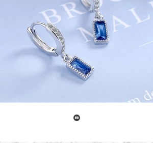 Detailed macro view of silver hoop earring with rectangular sapphire blue zircon stones