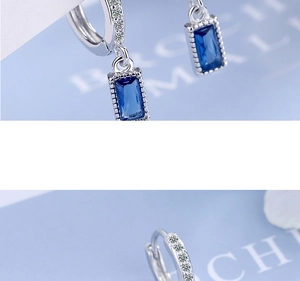 Macro shot of silver earrings with blue rectangular gemstone and white zircon detail