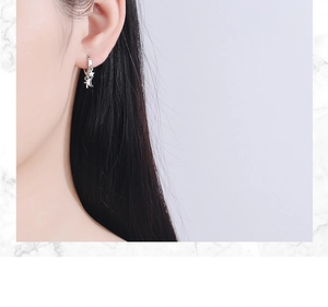 Close-up of star and moon charms on silver drop earrings worn by a model