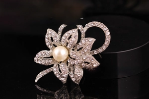 Detailed close-up of a silver flower brooch with crystal petals and a large center pearl